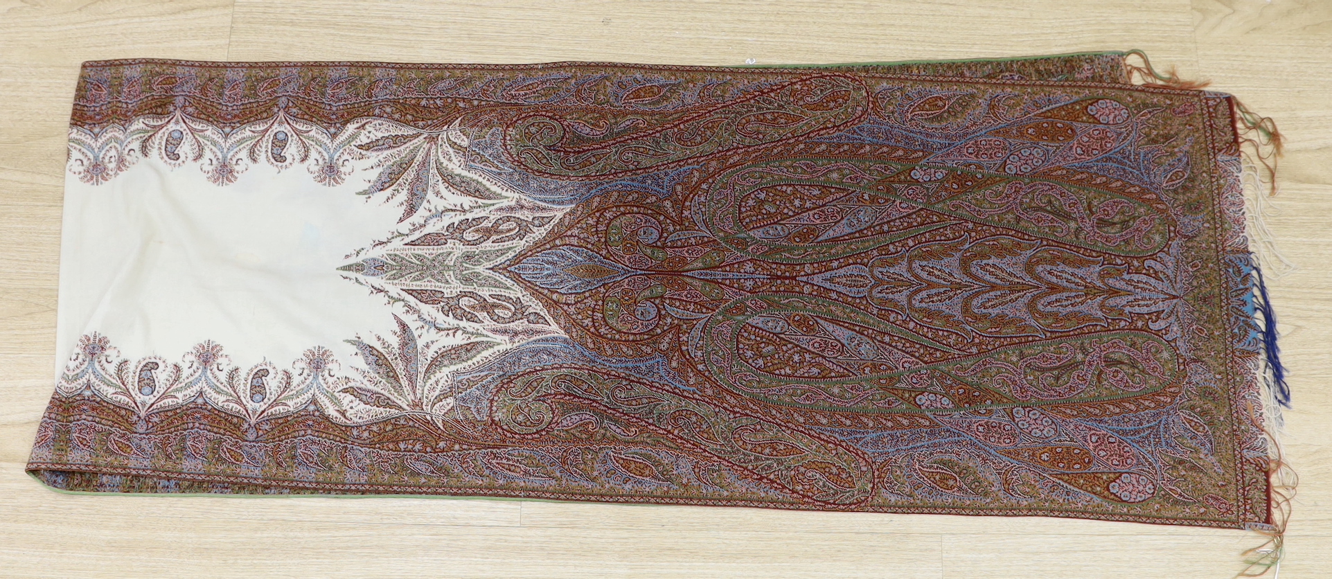 An Indian cream ground paisley stole with un-woven cream centre and heavily woven multicoloured borders and ends, both fringed, 273 x 52cm